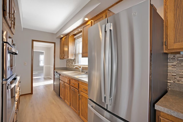 kitchen featuring appliances with stainless steel finishes, light hardwood / wood-style floors, tasteful backsplash, and sink