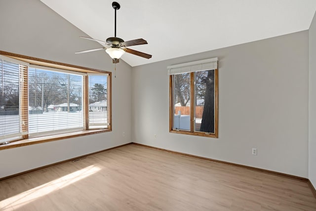 spare room with a healthy amount of sunlight, lofted ceiling, light hardwood / wood-style flooring, and ceiling fan