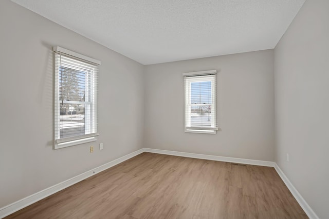 empty room featuring light wood-type flooring and a textured ceiling