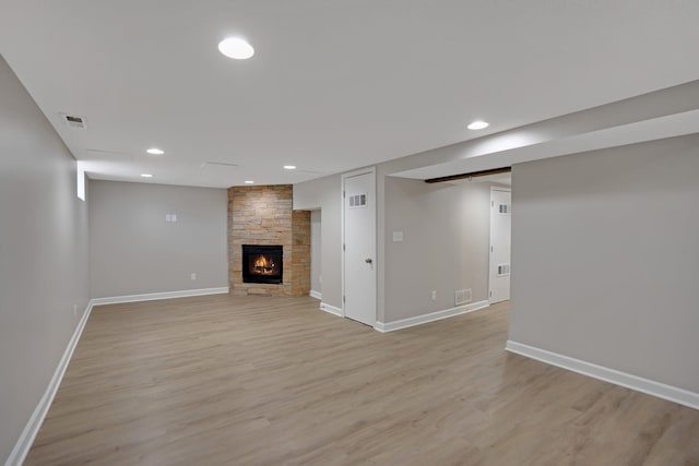 basement with a stone fireplace and light hardwood / wood-style flooring