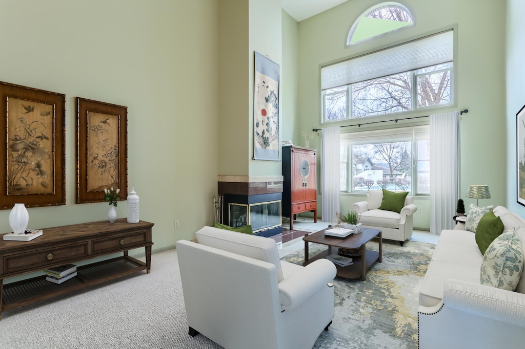 living room with light carpet, a towering ceiling, and a multi sided fireplace