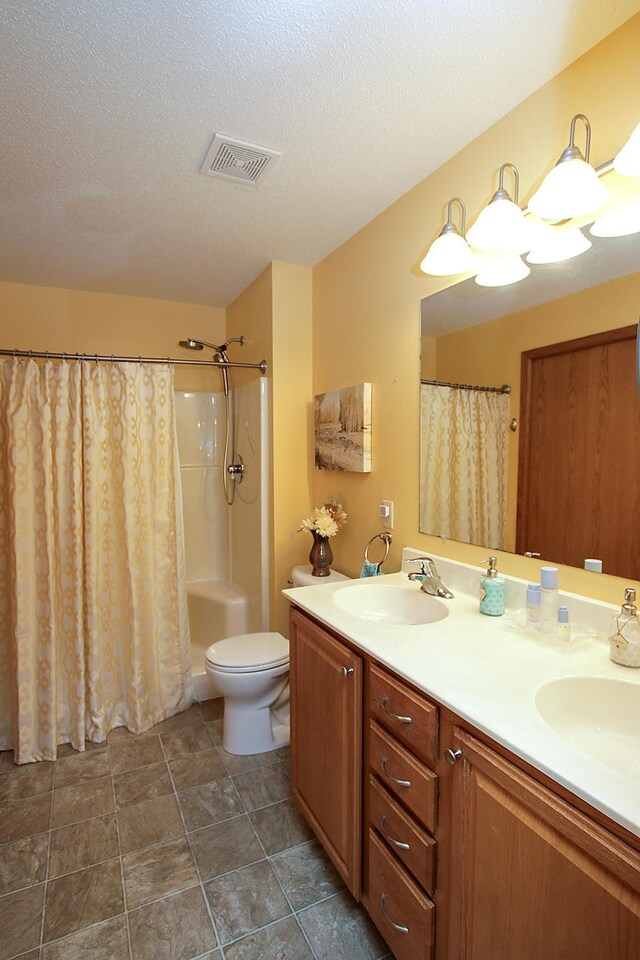 1406 Elsie Dr, Glencoe, MN 55336 - bathroom featuring curtained shower, toilet, double vanity, and a textured ceiling