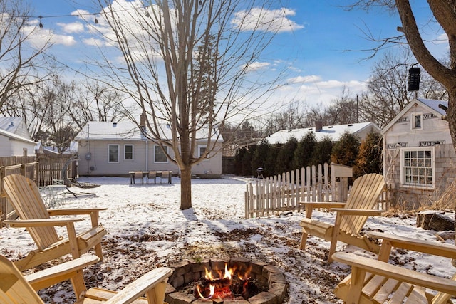 snowy yard featuring a storage shed and a fire pit