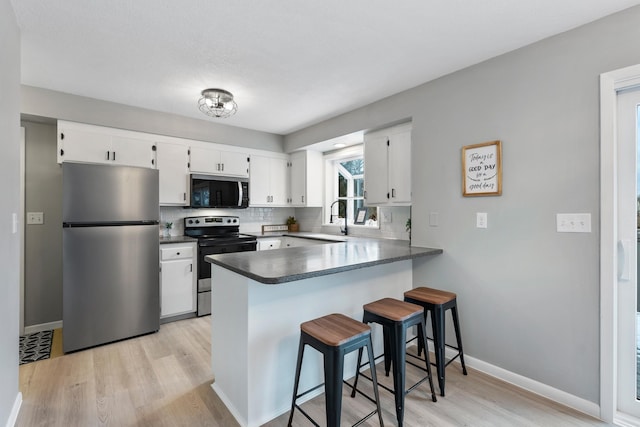 kitchen featuring stainless steel appliances, white cabinetry, tasteful backsplash, and kitchen peninsula