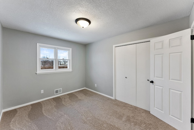 unfurnished bedroom with a closet, a textured ceiling, and carpet