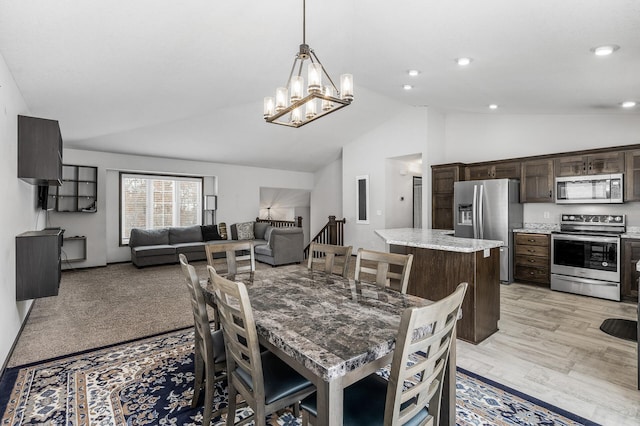 dining area with a chandelier, lofted ceiling, and light hardwood / wood-style floors