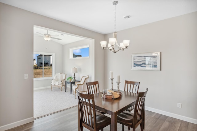 dining room featuring wood-type flooring, vaulted ceiling, and ceiling fan with notable chandelier