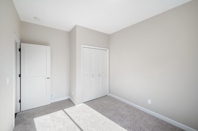 unfurnished bedroom with light colored carpet and a closet