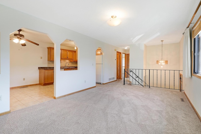 empty room with light carpet, a sink, visible vents, and baseboards