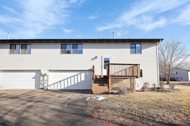 view of front of home with a garage, aphalt driveway, and a wooden deck