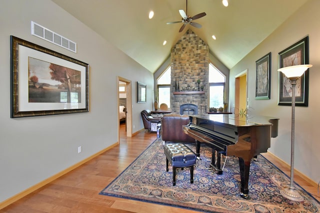 miscellaneous room featuring ceiling fan, a large fireplace, light hardwood / wood-style floors, and high vaulted ceiling