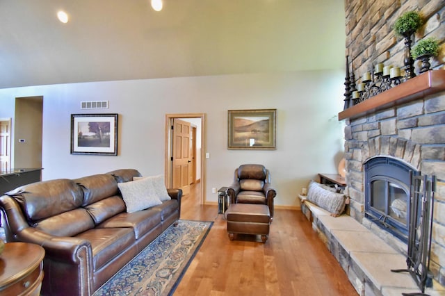 living room with a stone fireplace and light hardwood / wood-style flooring