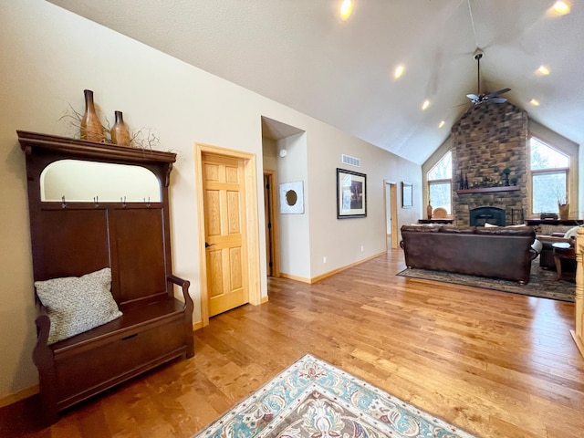 living room featuring ceiling fan, wood-type flooring, a fireplace, and high vaulted ceiling