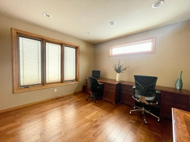 home office featuring a textured ceiling and light hardwood / wood-style flooring