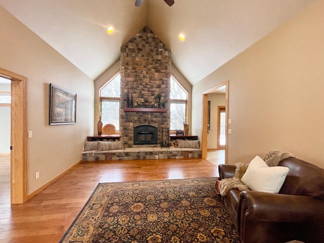 living room featuring a fireplace, high vaulted ceiling, ceiling fan, and light wood-type flooring