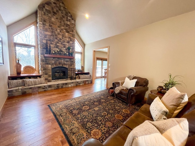 living room featuring a stone fireplace, hardwood / wood-style floors, and high vaulted ceiling