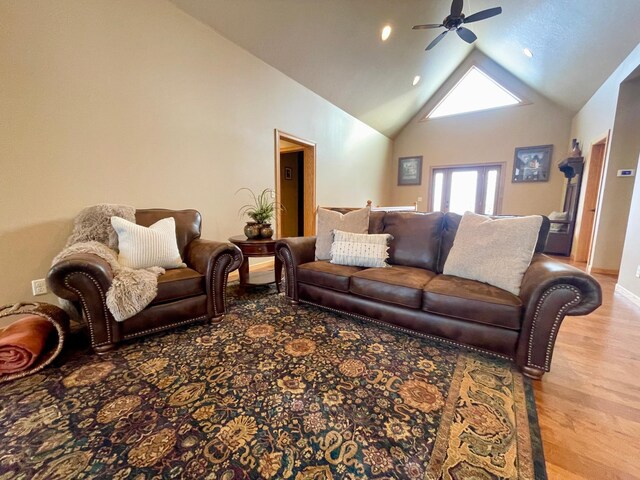 living room with ceiling fan, high vaulted ceiling, and light wood-type flooring