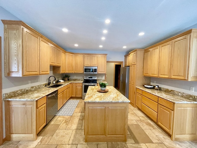 kitchen featuring light brown cabinetry, sink, light stone counters, a center island, and appliances with stainless steel finishes