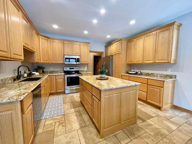 kitchen featuring sink, appliances with stainless steel finishes, a center island, light stone counters, and light brown cabinetry