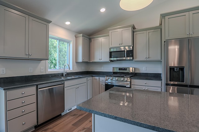 kitchen with sink, gray cabinetry, stainless steel appliances, and vaulted ceiling