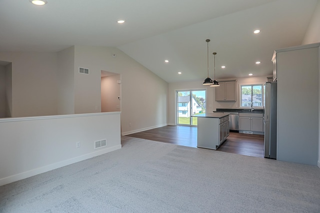 kitchen featuring appliances with stainless steel finishes, gray cabinetry, hanging light fixtures, vaulted ceiling, and a center island