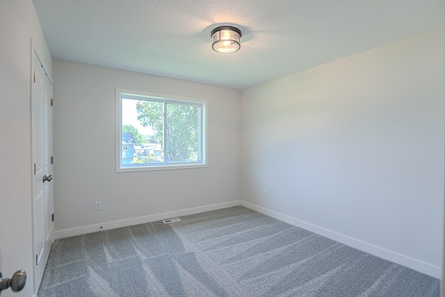 carpeted empty room featuring a textured ceiling