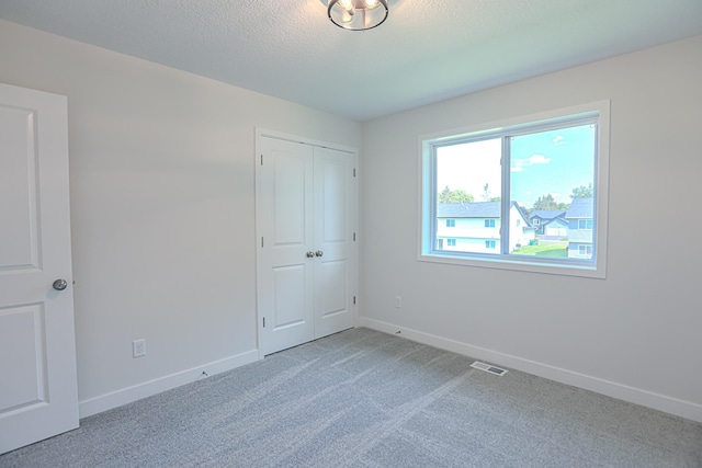 unfurnished bedroom featuring carpet floors, a textured ceiling, and a closet