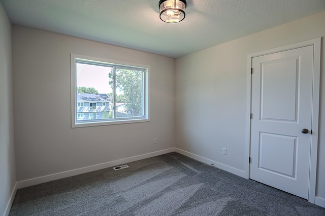 carpeted empty room featuring a textured ceiling