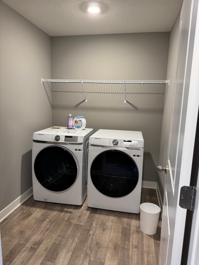 clothes washing area featuring dark wood-type flooring, washer and dryer, and a textured ceiling