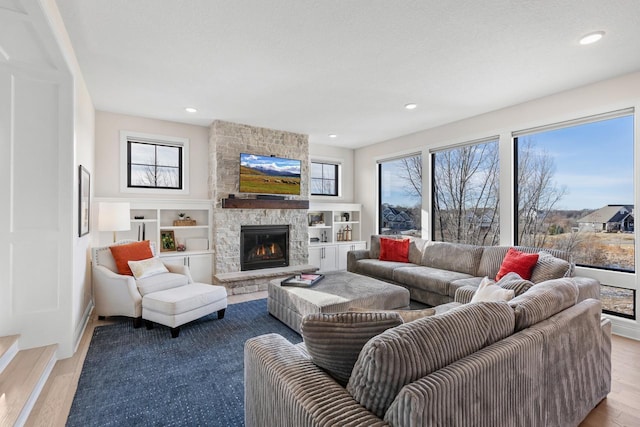 living room with a fireplace, a healthy amount of sunlight, and light wood-type flooring