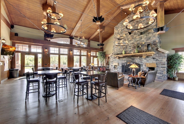 unfurnished dining area with wooden ceiling, hardwood / wood-style floors, a stone fireplace, high vaulted ceiling, and a notable chandelier