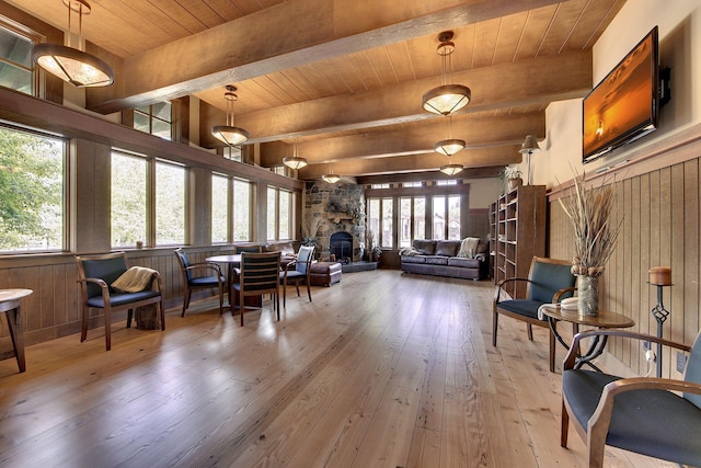 living area featuring beam ceiling, wooden ceiling, a fireplace, and hardwood / wood-style floors