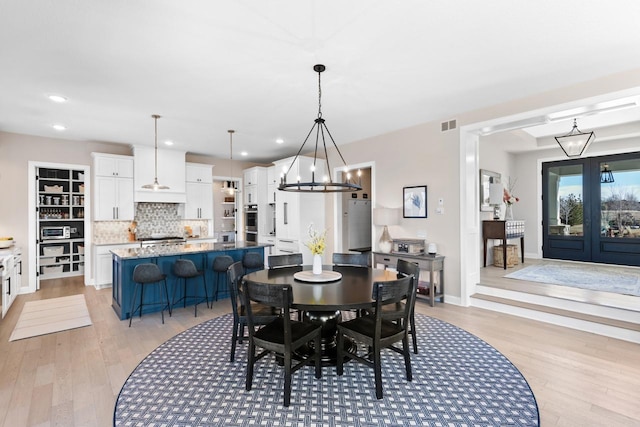 dining room featuring a chandelier, light wood-type flooring, and visible vents