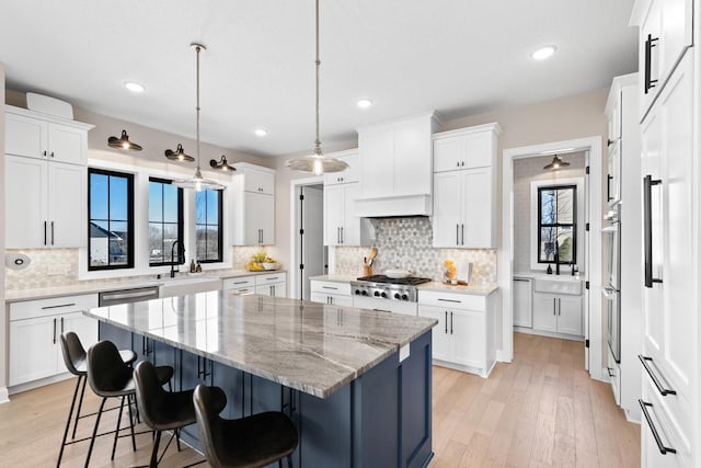 kitchen featuring stainless steel gas cooktop, a breakfast bar area, white cabinets, and a center island