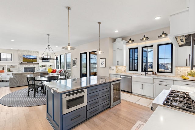 kitchen with stainless steel appliances, wine cooler, white cabinets, and a sink