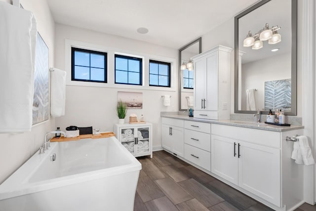 bathroom with a freestanding tub, wood finished floors, and vanity