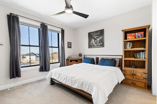 carpeted bedroom with a ceiling fan, visible vents, and baseboards