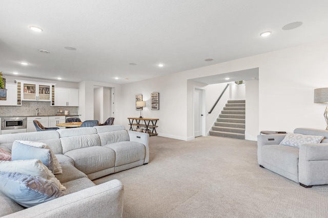 living room with recessed lighting, light colored carpet, stairway, and wet bar