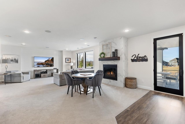 carpeted dining room featuring baseboards, a high end fireplace, and recessed lighting