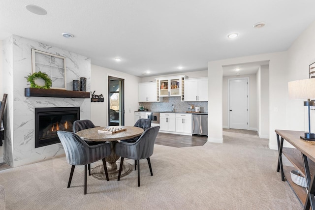 dining area featuring baseboards, light colored carpet, a premium fireplace, wet bar, and recessed lighting