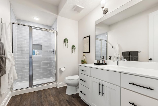 full bath with toilet, wood finished floors, visible vents, vanity, and a stall shower