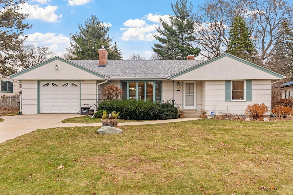 ranch-style house featuring a garage and a front lawn