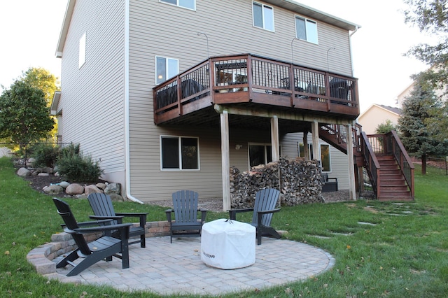 back of house featuring a lawn, a deck, a patio, and a fire pit