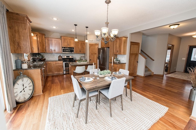 dining room with light hardwood / wood-style floors, sink, and an inviting chandelier