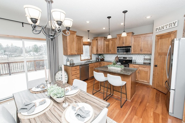 kitchen with appliances with stainless steel finishes, a center island, sink, hanging light fixtures, and a chandelier