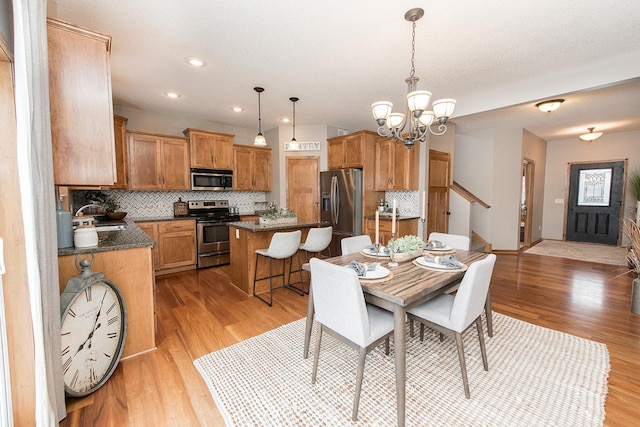 dining space featuring sink, an inviting chandelier, and light hardwood / wood-style flooring