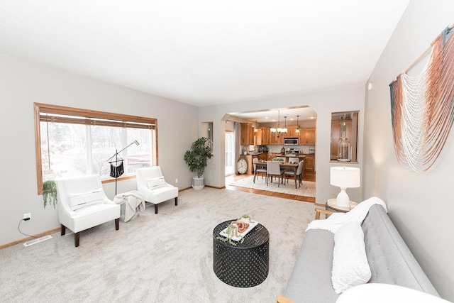 living room featuring light colored carpet and an inviting chandelier