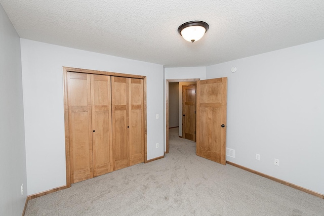 unfurnished bedroom featuring light colored carpet, a closet, and a textured ceiling