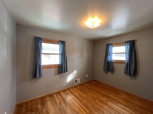 unfurnished room featuring hardwood / wood-style flooring, a wealth of natural light, and a textured ceiling