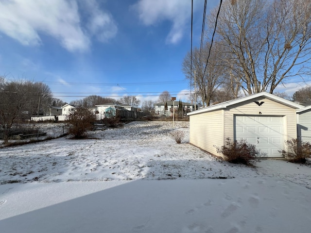 yard covered in snow featuring a garage and an outdoor structure